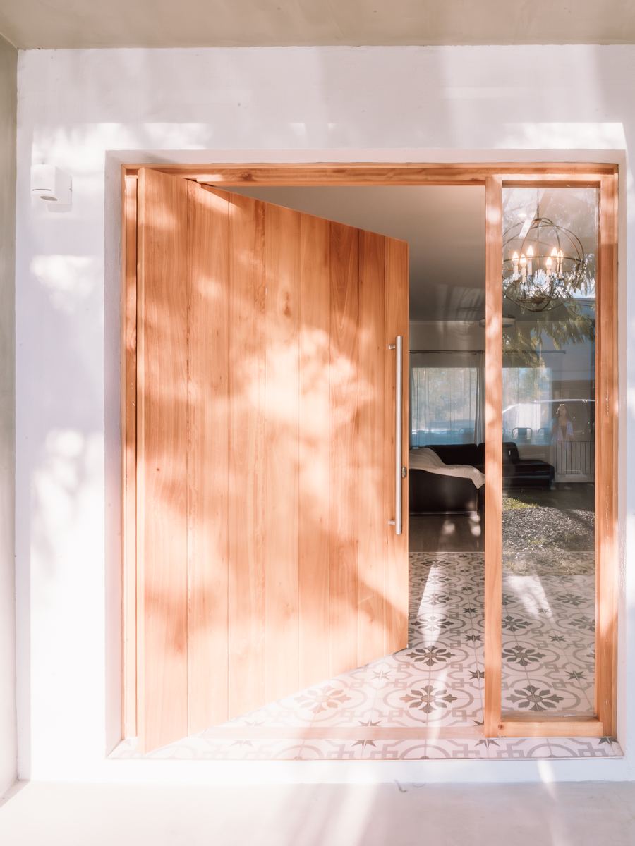 Puerta pivotante de madera y piso calcáreo del hall