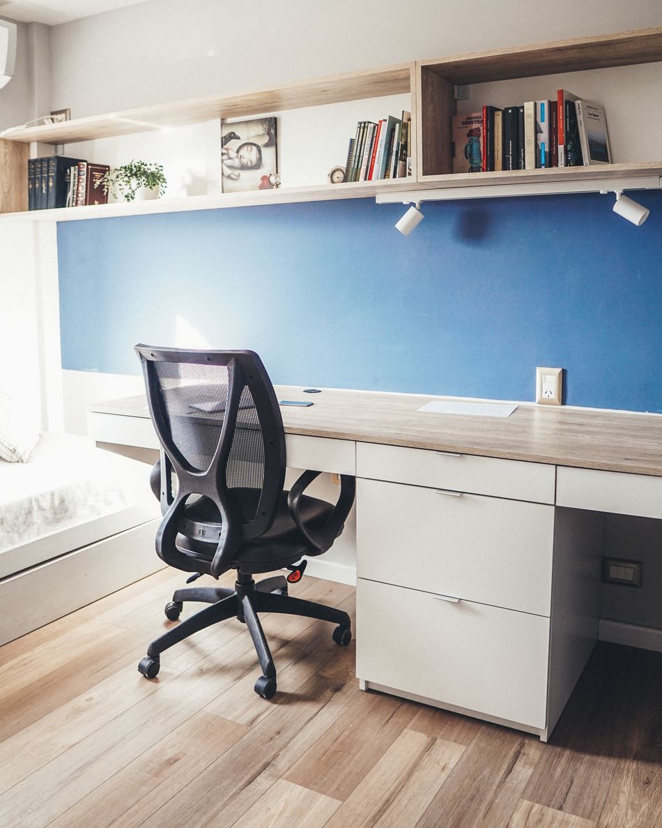 Estudio con escritorio corrido a medida y biblioteca sobre pared azul